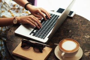 Hands of young woman using laptop in cafe