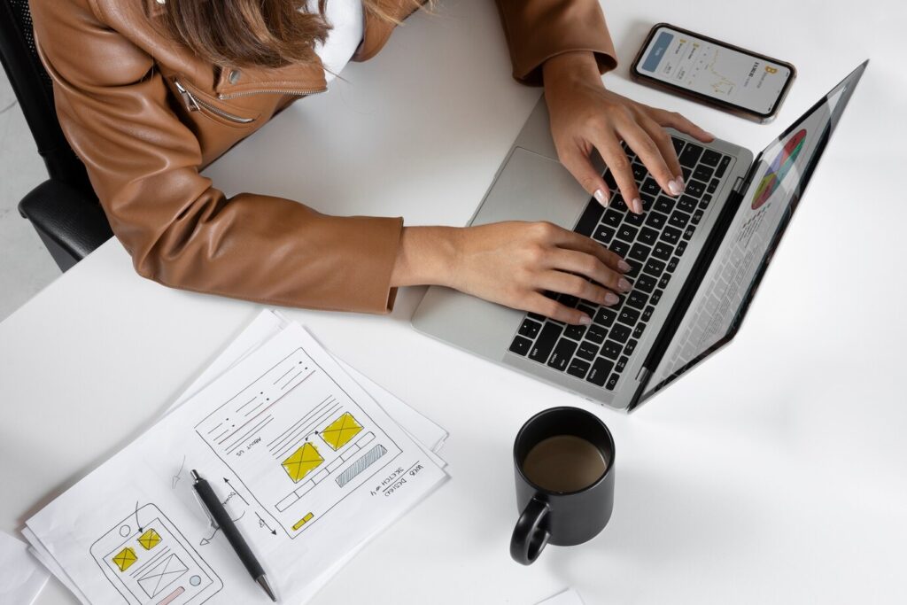 person in a brown leather jacket types on a laptop