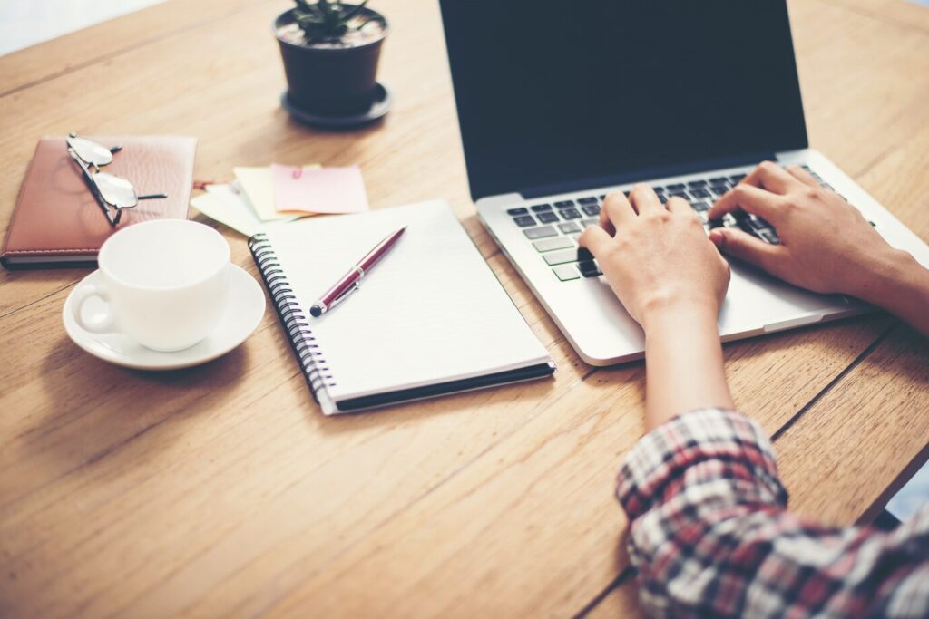 person in a checked shirt typing on a laptop