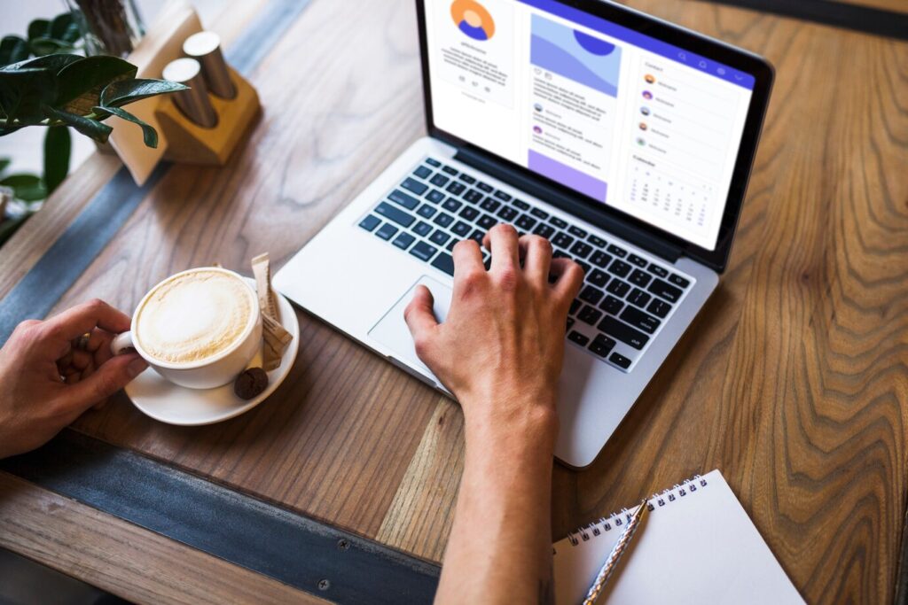 person's hand using a laptop on a wooden table