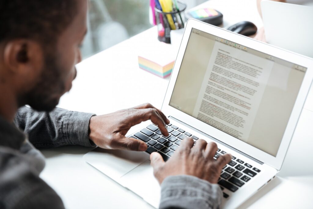 person types on a laptop with notes