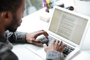 person types on a laptop with notes