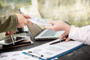 person hands a stack of cash to another