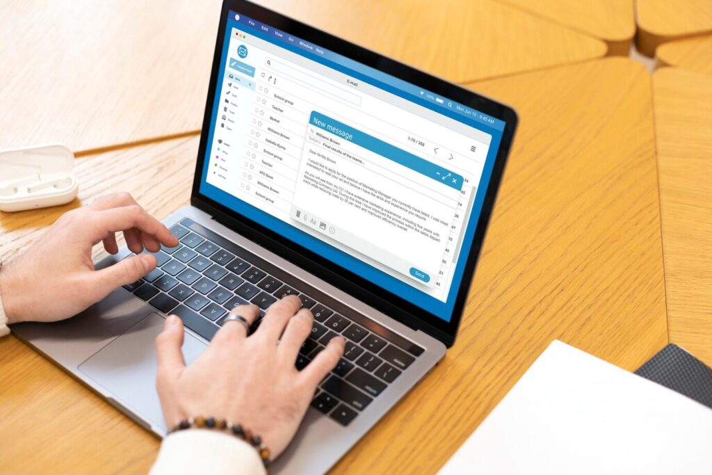person typing on a laptop displaying an email interface