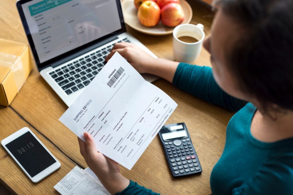 person evaluates a shipping receipt while working on a laptop