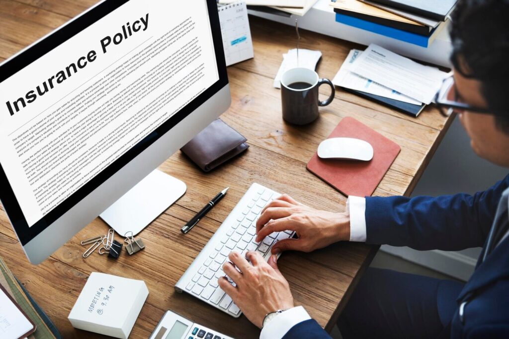 employee in a suit types on a keyboard, with an insurance policy
