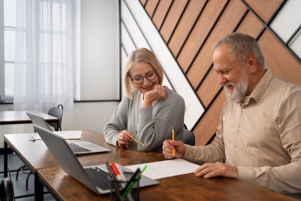 people engage in discussion at a desk with a laptop and documents