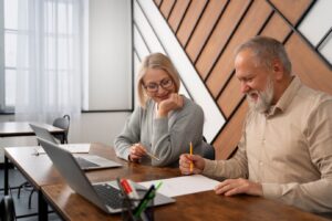 people engage in discussion at a desk with a laptop and documents