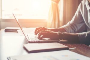 person types on a laptop in a sunlight room