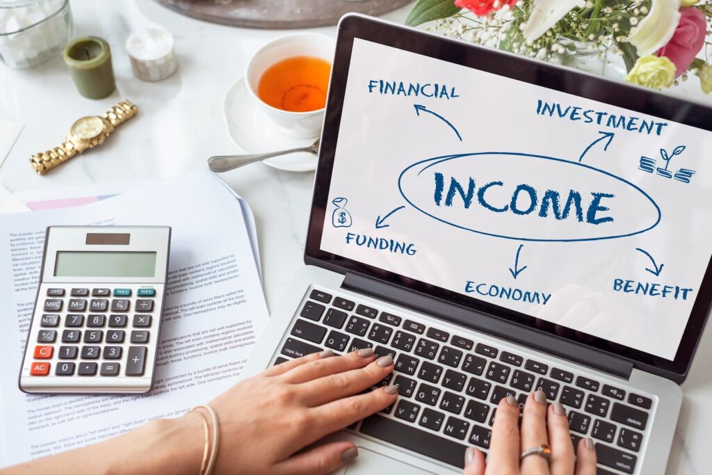 laptop displaying a flowchart on income, surrounded by a calculator