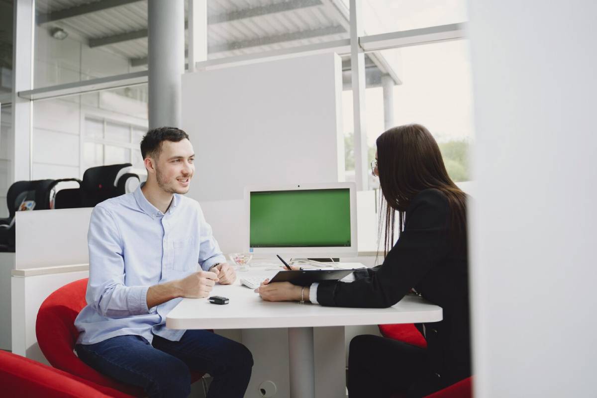 Two people discussing work at a modern office table, in a bright, airy office space.