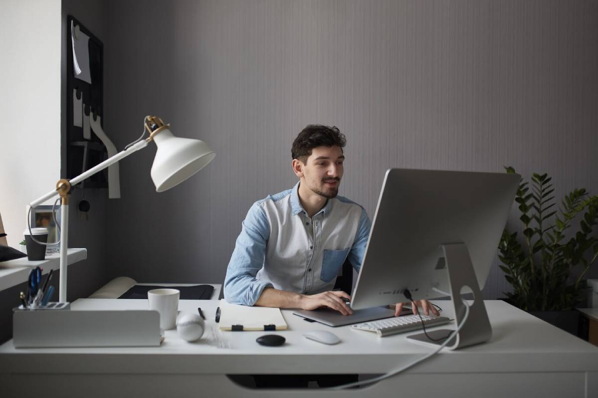 Man working at a desk with a computer in a modern, well-lit office.